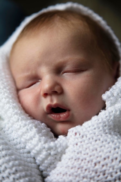 Ein einmonatiges schlafendes Baby, eingehüllt in eine weiße Decke