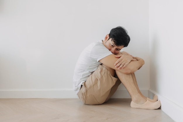 Ein einsamer depressiver Mann sitzt in der Ecke des Raumes