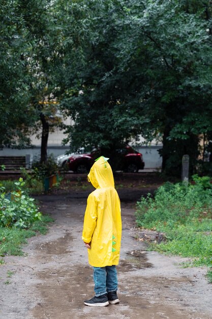 Ein einsamer Junge in einem gelben Regenmantel hat sich im Park verirrt