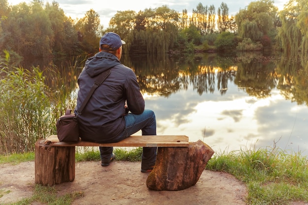 Ein einsamer Mann sitzt auf einer Bank am See. dachte der einsame Mann.