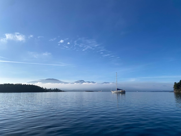 Ein einzelnes Segelboot vor Anker mit ruhigem Wasser und blauem Himmel Gulf Islands British Columbia Kanada