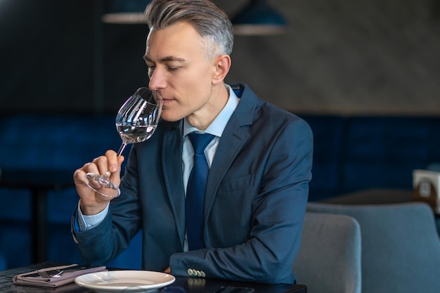 Ein eleganter Mann, der Weißwein probiert und zufrieden aussieht
