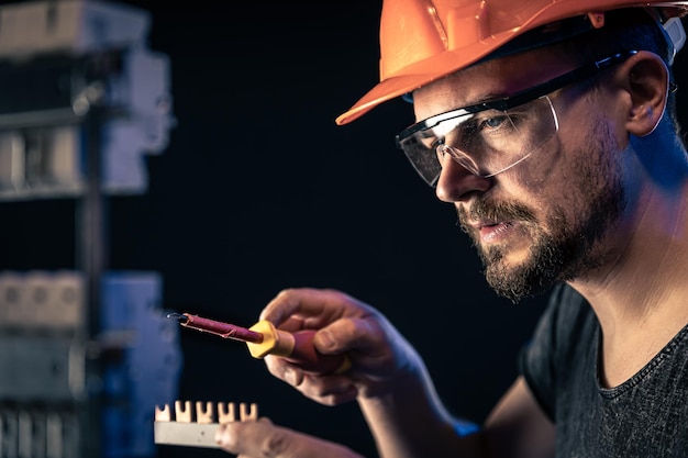 Ein Elektriker arbeitet in einer Schalttafel mit einem elektrischen Verbindungskabel