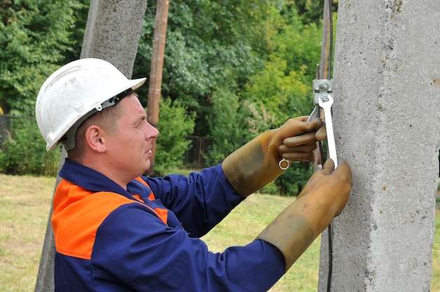 Ein Elektriker erdet einen Strommast