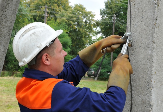 Ein Elektriker erdet einen Strommast