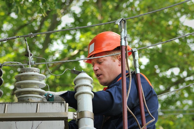 Ein Elektriker ersetzt einen beschädigten Isolator an einer geerdeten Stromleitung