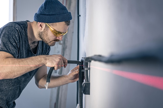 Ein Elektriker montiert Steckdosen an der weißen Wand im Haus