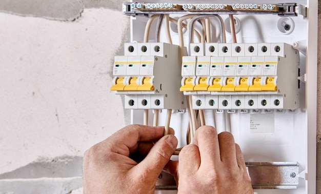 Ein Elektriker verbindet Drähte mit dem Sicherungskasten in der Verbrauchereinheit der Schalttafel