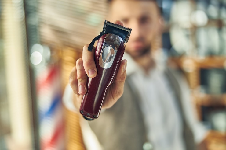 Foto ein elektrischer haarschneider in der hand eines erfahrenen friseurs auf einem hintergrund