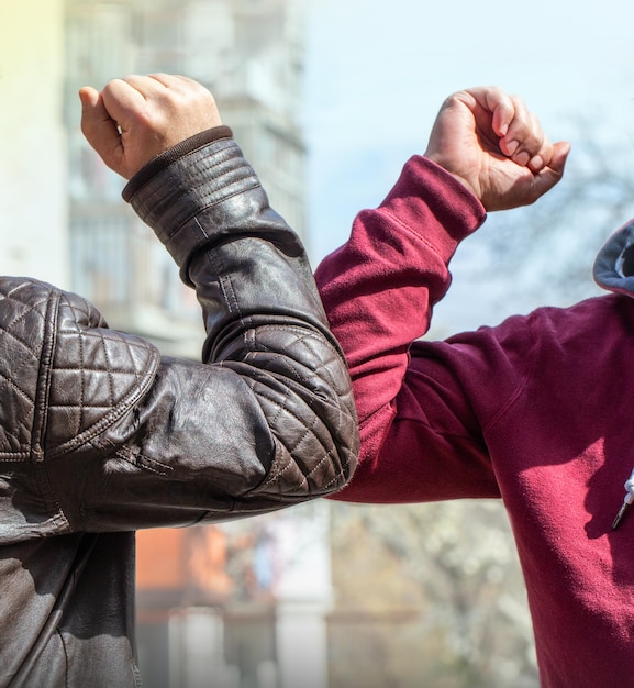 Ein Ellbogen Ein neuer Gruß, um die Ausbreitung des Coronavirus zu vermeiden, wenn sich zwei Freunde auf der Straße treffen