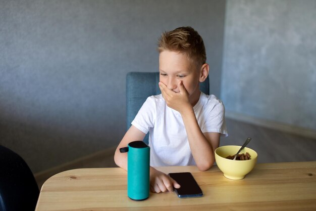 Ein emotionaler Junge in einem weißen T-Shirt verbindet den Lautsprecher mit dem Telefon und lacht