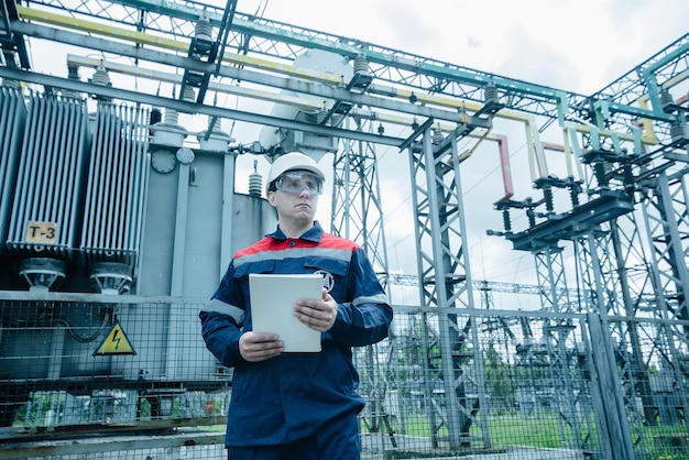 Ein energietechniker inspiziert die moderne ausrüstung einer umspannstation vor der inbetriebnahme. energie und industrie planmäßige reparatur von elektrischen geräten