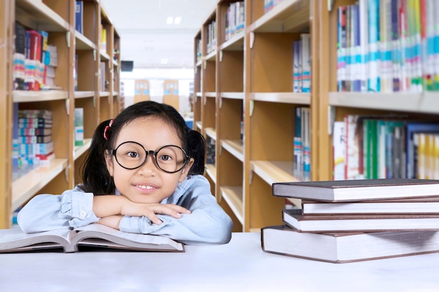 Ein entzückendes Schulmädchen sitzt mit Lehrbüchern