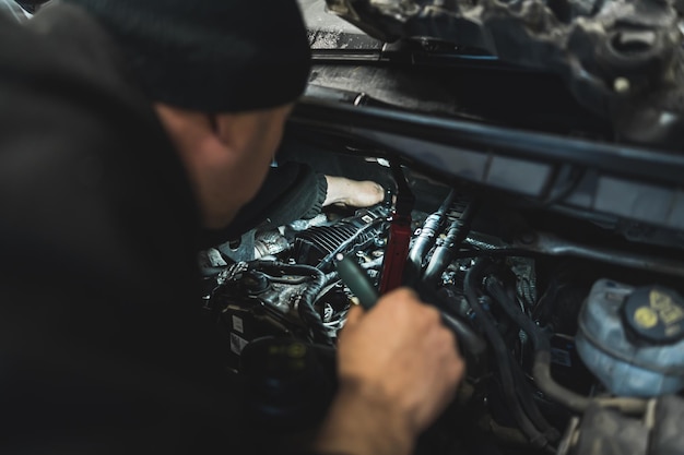 Ein erfahrener Mechaniker arbeitet fleißig an einem Auto mit angehobener Motorhaube, um den Motor freizulegen