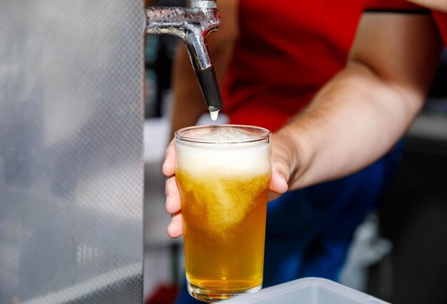 Ein erfrischendes Bier aus dem Wasserhahn in ein Glas in einer Bar gießen