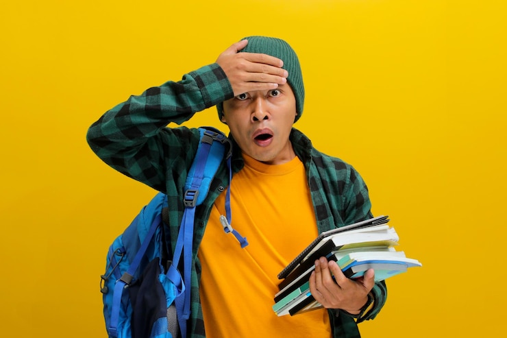 Foto ein erschrockener junger asiatischer student zeigt einen schockierten ausdruck mit einer hand auf dem kopf, während er ein buch liest