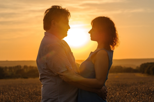 Ein erwachsener Bauer und seine Frau umarmen sich auf ihrem Weizenfeld.