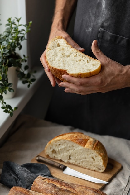 Ein erwachsener europäischer Bäcker hält ein rundes frisches Brot in den Händen, ein Mann in einer Bäckerei hält ein