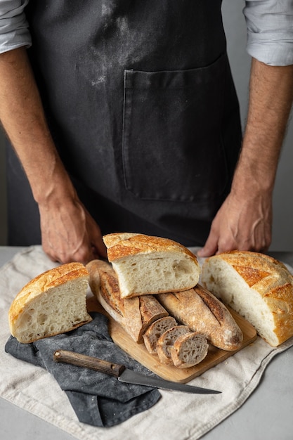 Ein erwachsener europäischer Bäcker hält ein rundes frisches Brot in den Händen, ein Mann in einer Bäckerei hält ein