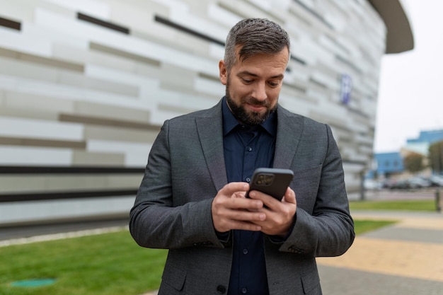 Ein erwachsener Geschäftsmann in einem klassischen Anzug blickt überrascht auf den Telefonbildschirm