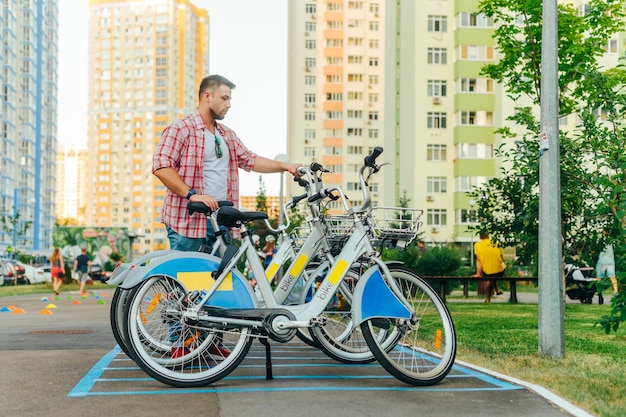 Ein erwachsener Mann in einem Hemd mietet am Wochenende ein Fahrrad für einen Spaziergang