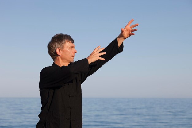 Ein erwachsener Mann trainiert am Strand vor klarem Himmel.