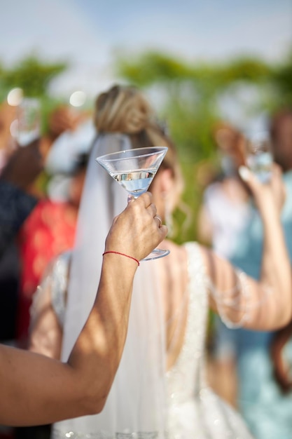 Foto ein europäisches mädchen hält ein martini-glas in den händen vor dem hintergrund der gäste einer hochzeitsfeier