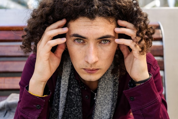 Ein extremes Nahaufnahmeportrait eines jungen lateinischen Mannes mit lockigem Haar und ernstem Gesicht.