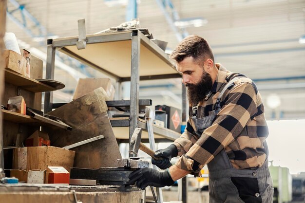 Ein Fabrikarbeiter benutzt einen Hammer in einer Anlage