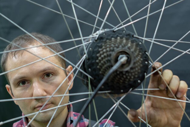 Foto ein fahrradmechaniker hält ein rad von einem fahrrad fahrradreparatur radspeichen und kassette von einem mountainbike auf schwarzem hintergrund