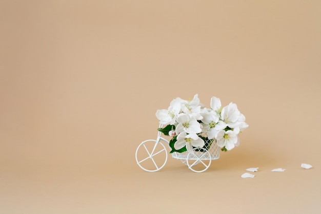 Ein Fahrradspielzeug mit weißen Blumen auf beigem Hintergrund Das Konzept des Feierbanners