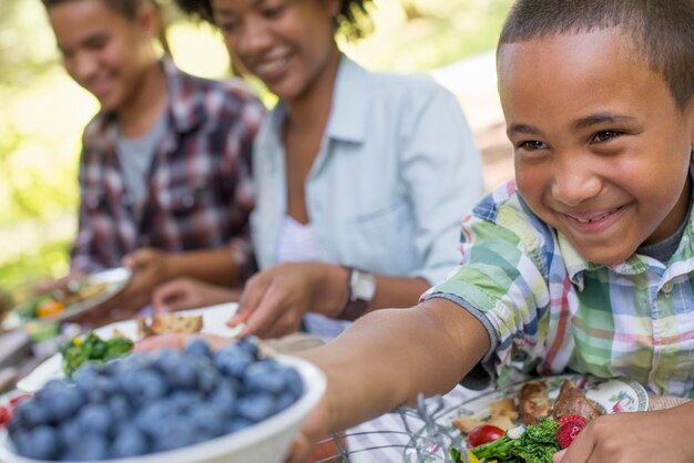 Ein Familienpicknick in einem schattigen Waldgebiet Erwachsene und Kinder sitzen an einem Tisch