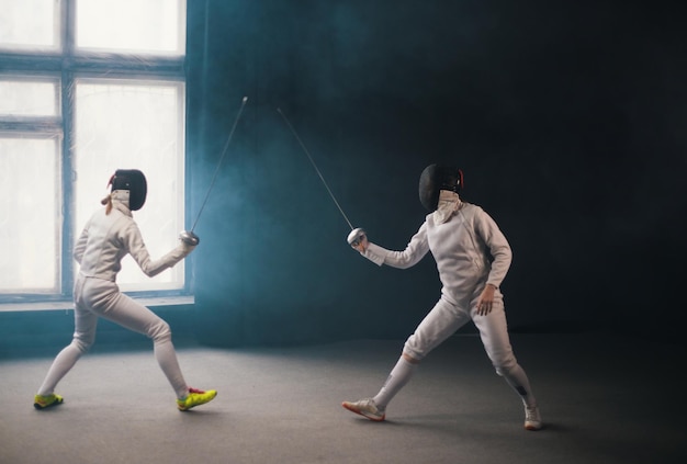 Ein Fechttraining im Studio Zwei Frauen in Schutzanzügen beim Duell