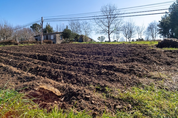 Ein Feld aus Erde und Gras mit einem Haus im Hintergrund