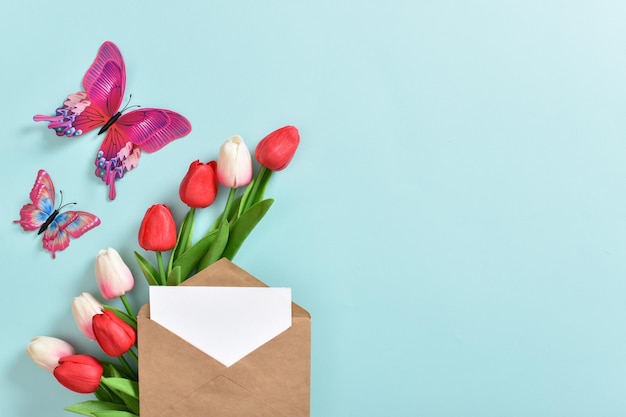 Ein festliches Banner mit Tulpen und einem Umschlag auf hellblauem Hintergrund Muttertag Frauentag alles Gute zum Geburtstag Kopierbereich Flache Ansicht von oben