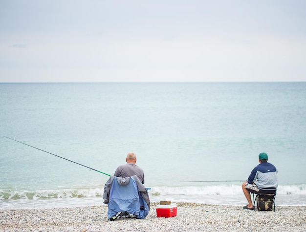 Ein Fischer mit einer Stange im Ozean fängt am frühen Morgen Fische