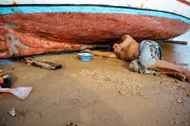 ein Fischer repariert den zerstörten Boden seines Bootes mit Nägeln und Zement