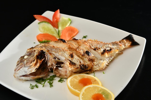 Ein Fischteller mit Zitronen und Tomaten darauf