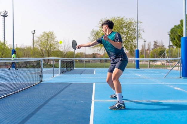 Ein fitter junger Mann spielt Pickleball auf einem Außenplatz