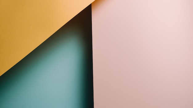 Ein flacher gelber, rosa und blauer Pastellhintergrund mit scharfen Schichten und Schatten mit Kopierraum