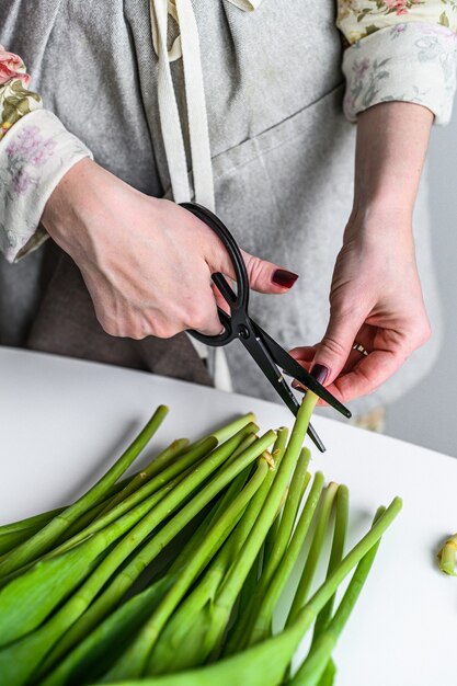 Ein Floristenmädchen mit einer Schere in den Händen macht einen Strauß aus gelben, orangefarbenen und roten Tulpen