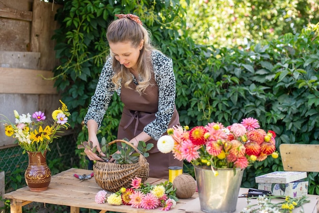 Ein Floristenmädchen sammelt einen Strauß Herbstblumen in einem Korb