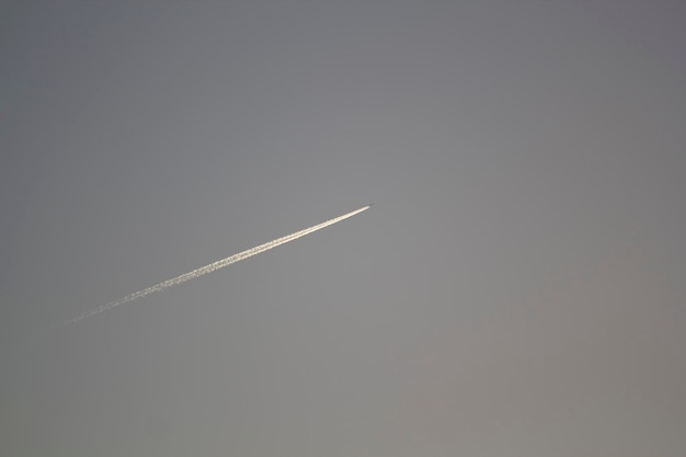 Ein Flugzeug fliegt am Himmel mit einer Spur im Himmel.