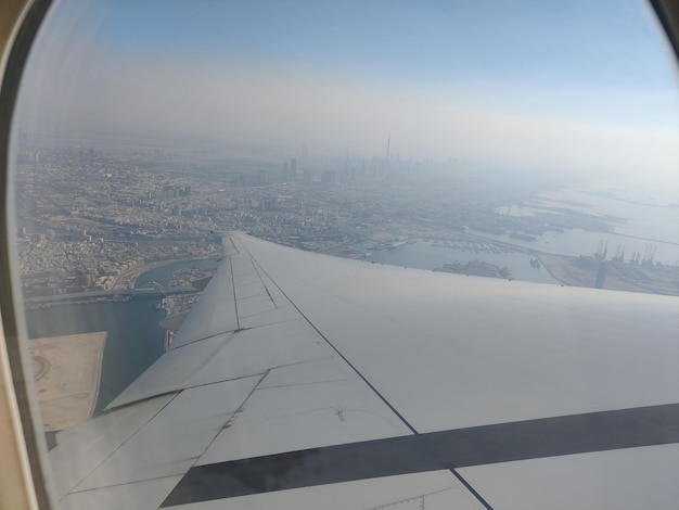 Ein Flugzeug fliegt über einer Stadt und der Himmel ist blau.