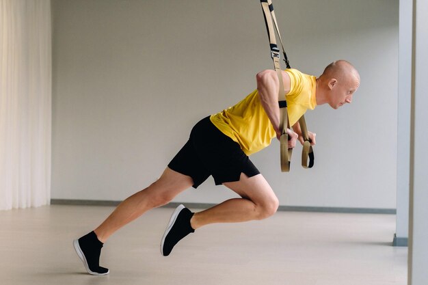 Ein fokussierter männlicher Athlet, der im Fitnessstudio eine Übung an Funktionsschleifen durchführt.
