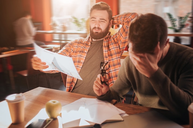 Ein Foto voller Verzweiflung. Zwei Freunde, die zusammenarbeiten, studieren Grafiken, die schwer zu verstehen sind. Sie machen das schon seit Stunden und verstehen es immer noch nicht. Das liegt daran, dass sie traurig sind.