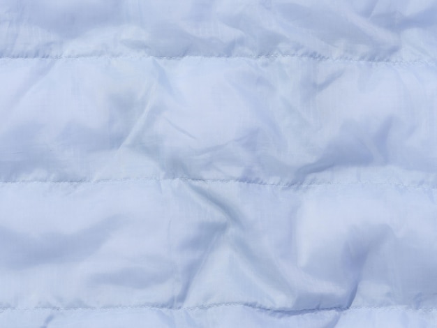 Ein Fragment aus blauem Stoff mit Daunenfüllung und Nähstoff für Jacken und Mäntel