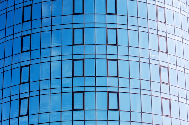 Ein Fragment eines modernen Hauses mit großen Fenstern, die einen blauen Himmel zeigen. Moderne Architektur mit Glaskonstruktionen