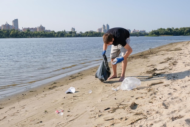 Foto ein freiwilliger mit einem müllsack sammelt müll an einem öffentlichen strand.