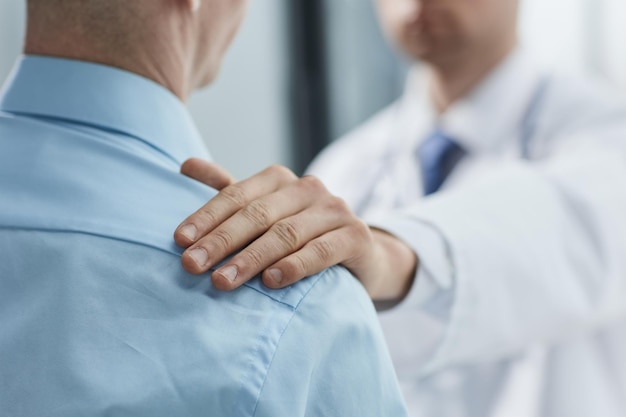 Ein freundlicher Arzt spricht mit einem männlichen Patienten und unterstützt und tröstet ihn während der Rezeption